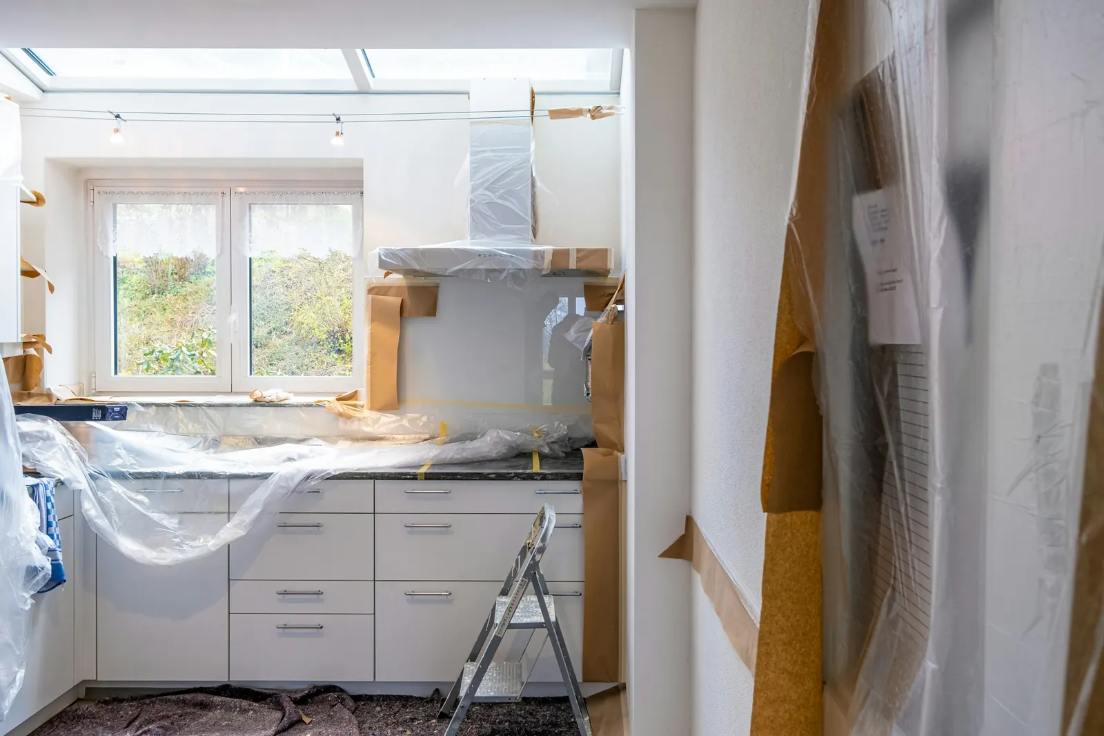 A kitchen during the job: cabinets installed, plastic sheeting and a ladder in the room