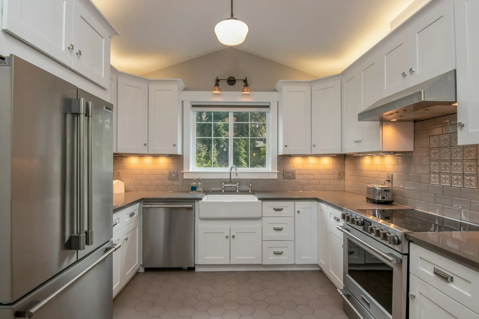 A white shaker kitchen with a farmhouse sink and lights under the wall cabinets